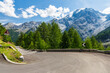 Sharp bend in Stelvio Pass in stunning sunlit Dolomites. Picturesque view of the snow capped mountain range above the winding asphalt road high in the Italian mountains.