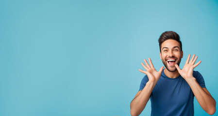 Joyful young man with a beard laughing and gesturing with hands, expressing excitement, isolated on a blue background, suitable for celebration and happiness concepts