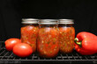 Handmade Canned Roasted Salsa Jars with Fresh Tomatoes Sitting on a Grill.
