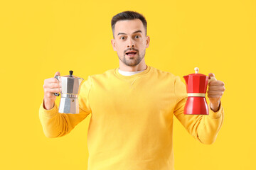 Canvas Print - Handsome man with geyser coffee makers on yellow background