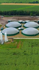 Wall Mural - Biogas plant on beautiful landscape. Bio gas production on green field in summer. Renewable energy on modern biofuel farm. Aerial view. Vertical video