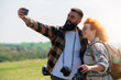 A beautiful and cheerful hiking couple captures a selfie with a stunning landscape in the background