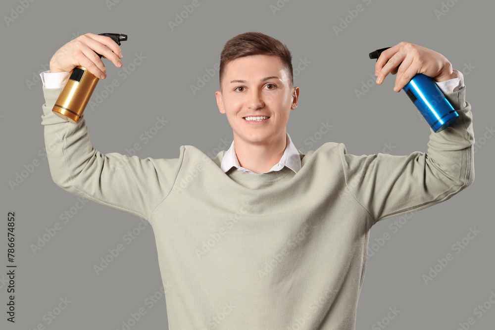 Male barber with hair sprays on grey background