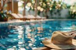 A hat resting on the edge of a sparkling swimming pool. Perfect for travel or summer themes