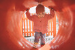 Smiling little girl entering playground's tube