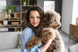 Young woman holding cute poodle at home