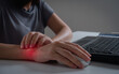 Young woman working in an office with carpal tunnel syndrome or wrist joint inflammation, massage on her hand and arm for relief pain from hard work for stiff, cramp symptom, carpal tunnel syndrome.