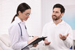 © New Africa - Doctor with clipboard consulting patient during appointment in clinic