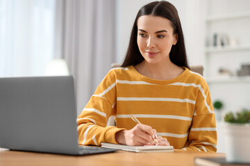 Poster - Young woman watching webinar at table in room