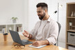 © New Africa - Young man using video chat during webinar at table in room