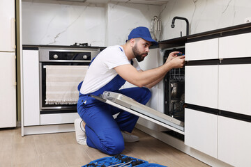 Sticker - Serviceman repairing dishwasher with screwdriver in kitchen