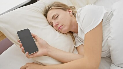 Canvas Print - A young woman sleeps in her bedroom, unknowingly holding a smartphone, showcasing an intimate and relaxed indoor moment.