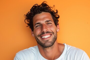 Wall Mural - Portrait of a handsome young man smiling against orange background with copy space