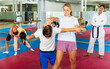 © JackF - Young boys and girls training self-defence moves during group training. Female trainer in kimono standing nearby and observing.