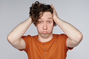 Wall Mural - Medium closeup studio portrait of young Caucasian man with curly hair demonstrating bewilderment, copy space