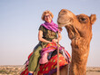 Joyful tourist riding camel in Jaisalmer desert
