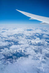 Wall Mural - aerial view through porthole of plane to of snow-covered mountain. scenic view through aircraft. air