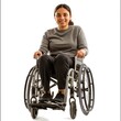 A smiling young woman in casual clothing seated in a wheelchair, portraying independence and positivity.