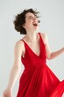 A woman in a vibrant red gown laughing with abandon, expressing pure joy and happiness.