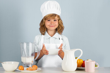 Cooking children. Chef kid boy making fresh vegetables for healthy eat. Portrait of little child in form of cook isolated on grey background. Kid chef. Cooking process.