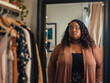 Body Positive Concept: Plus Size Woman Choosing Clothes in Home Wardrobe. Overweight Young Woman Holding Hangers with Blouses, Contemplating Fashion Choices in Front of Mirror