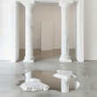 two hexagon white marble columns framing a minimalist white doorway with a silver mirror shaped like a puddle on the ground below the pillars with white walls and white floor