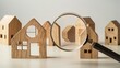 Search for housing and apartments. Real estate real using magnifying glass over the model of a wooden house.