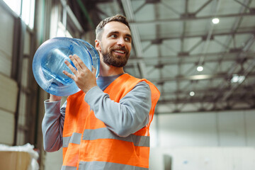 Wall Mural - Happy, confident, smiling worker wearing vest and workwear carrying water bottle, looking away