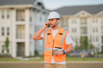 Wall Mural - Portrait of builder man. Construction worker with hardhat helmet on construction site. Construction engineer worker in builder uniform. Worker construction.