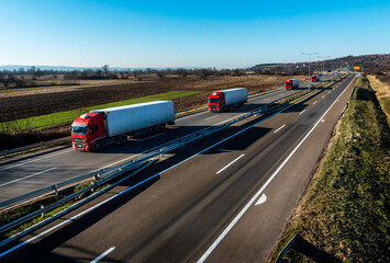 Wall Mural - Convoy of red Trucks with white containers on highway, cargo transportation concept in springtime - freight service