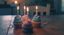 Three Cupcakes With Lit Candles On A Table, Suitable For Birthday Celebrations