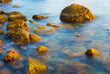 emerald calm sea bay with stones on coast, summer marine background