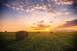 A field with haystacks on a summer or early autumn evening with a cloudy sky. Procurement of animal feed in agriculture. Rural landscape at sunset or sunrise.