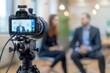© MD Media - A camera is placed on the tripod, with two business people standing in front of it for an interview video, selective focus of digital camera shooting businessman in office