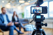 © MD Media - A camera is placed on the tripod, with two business people standing in front of it for an interview video, selective focus of digital camera shooting businessman in office