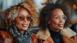 Wide angle close up of two fashionable, middle aged gorgeous women sitting in a black convertible with cognac colored seats