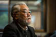 © AI_images - A Japanese businessman carefully listens to a discussion in a conference room setting.
