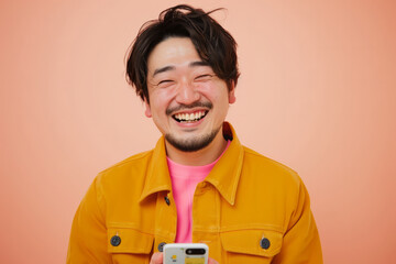 Wall Mural - A Japanese man smiles brightly while recommending a vibrant mobile app on a peach background, his positive energy contagious.