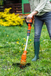 Grass trimmer. Woman is trimming grass in garden. Lawn care in spring