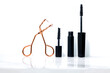 A display of lash tweezer and two small and big mascaras in a white background