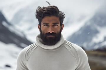 Wall Mural - Portrait of a glad indian man in his 20s showing off a thermal merino wool top in pristine snowy mountain