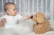 portrait of a 9 month old baby sitting in bed with a soft toy, girl with a stuffed dog
