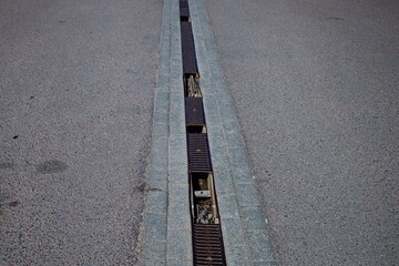 Wall Mural - A road with three types of road surface with asphalt paving stones, tiles and a gutter with rainwater drainage.