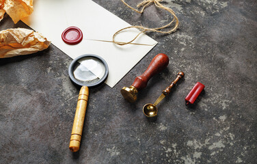 Wall Mural - Vintage postal stationery on concrete background. Blank envelope, sealing wax, stamp, spoon and magnifier.