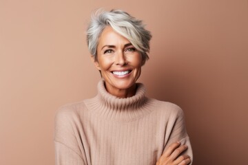 Wall Mural - Portrait of a jovial woman in her 50s wearing a cozy sweater over pastel brown background