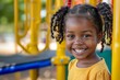 © Danko - Close up portrait of a smiling black girl happy child wearing colorful clothes, intense looking, on a playground.