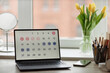 Background image of laptop computer with calendar on screen at workplace table by window with flowers, copy space