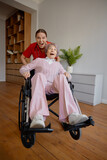 Fototapeta Tęcza - Crazy woman caregiver riding fast elderly woman patient on wheelchair