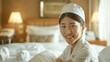 A professional photo, trending on Adobe Stock. A Japanese chambermaid in a neat uniform smiles warmly as she smoothing out the fitted sheet on a bed
