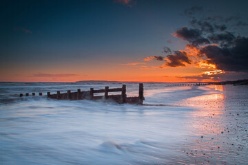 sunset on the beach long exposure camber sands east sussex clear evening summer red sky minimalistic blue and orange colours sea defence tourist hotspot 